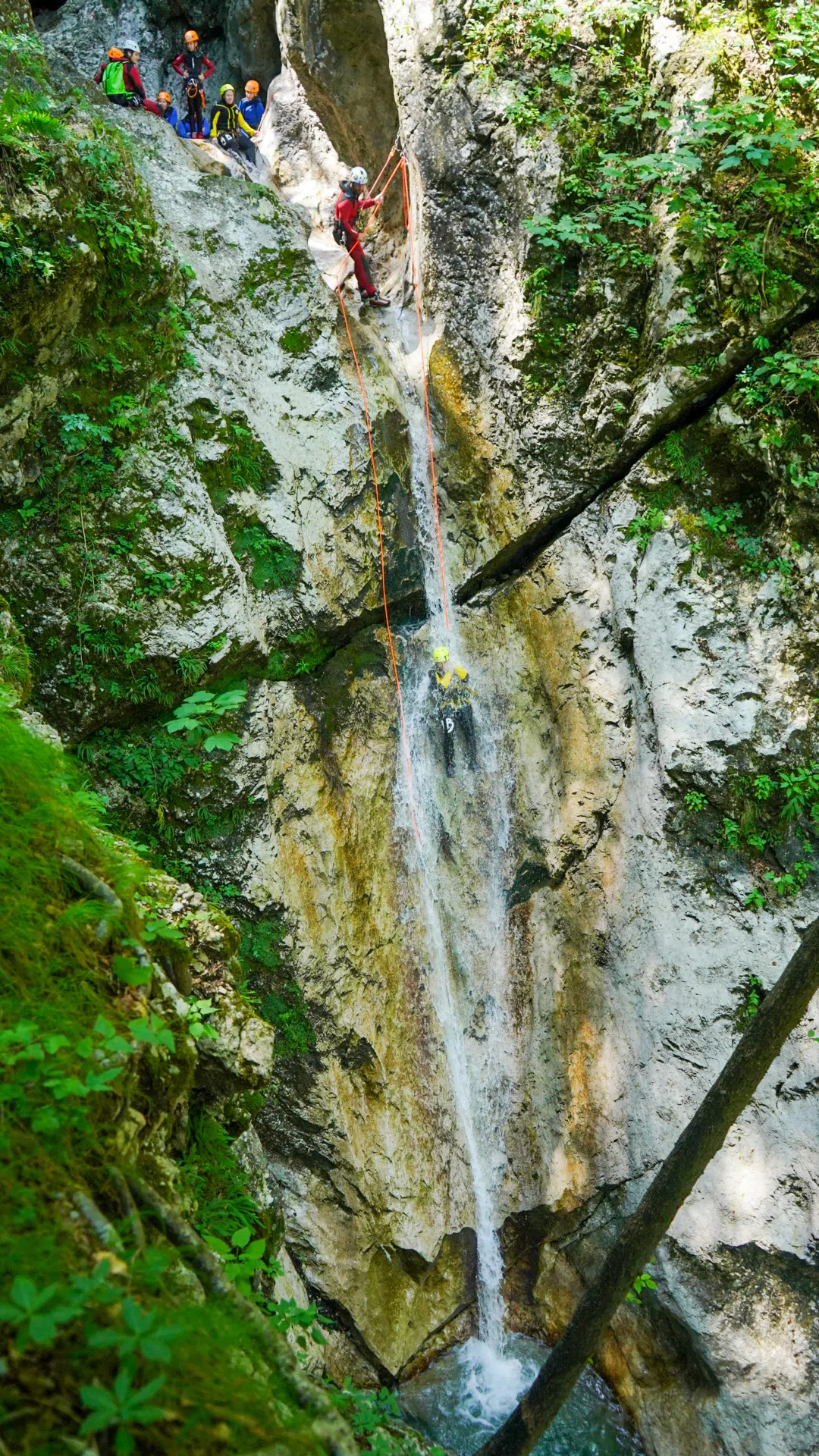 Canyoning participant descending beside a waterfall